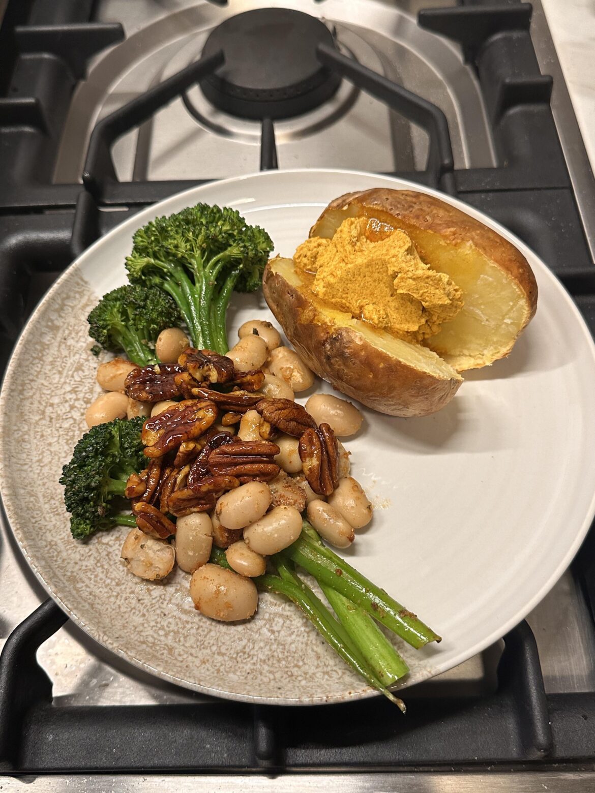 Baked potato with compound butter, broccolini, white beans, and spicy glazed pecans