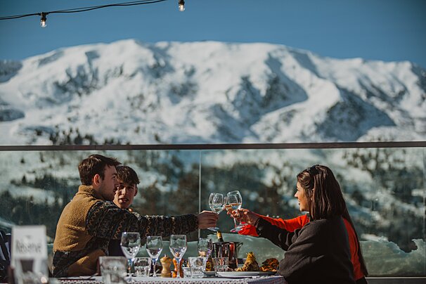 A group of people toasting with wine glasses in front of a snowy mountain