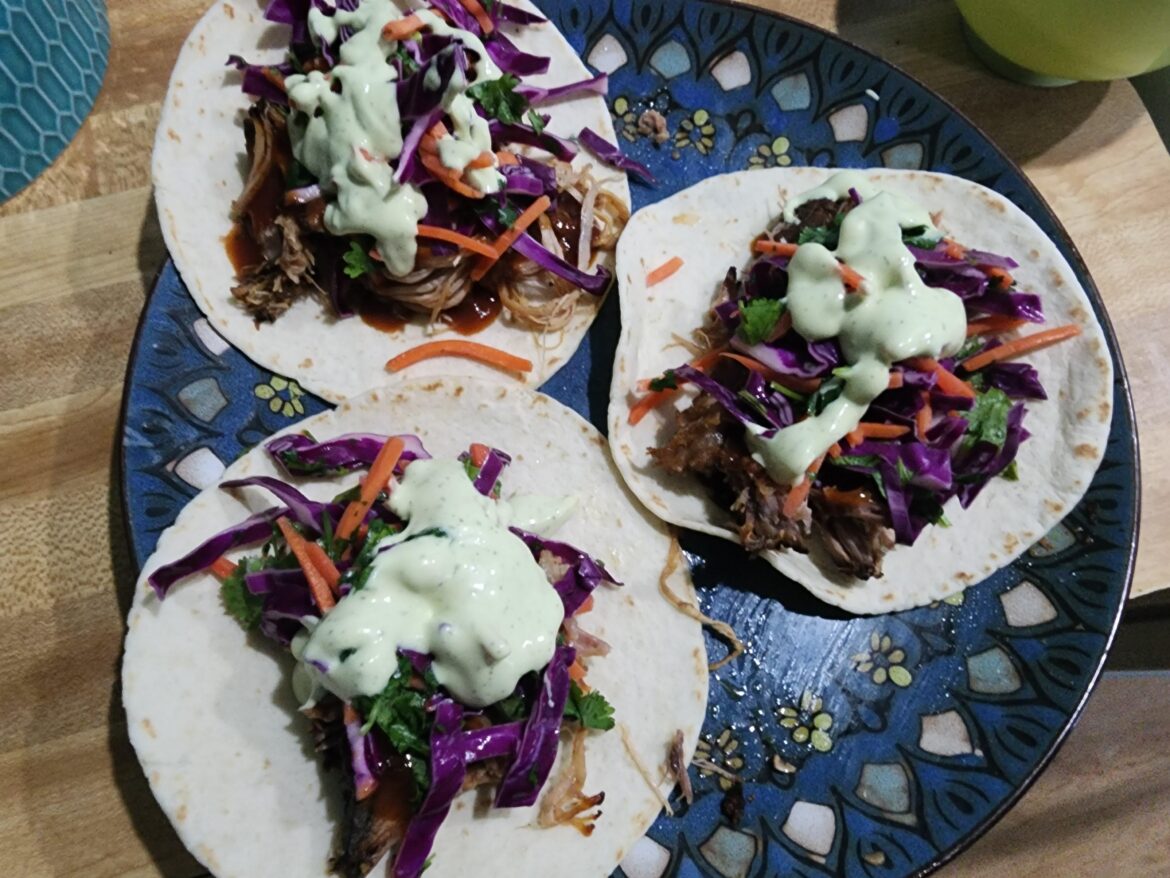 Smoked pork butt with a drizzle of Kinders gold, homemade cilantro lime slaw and avocado creme sauce