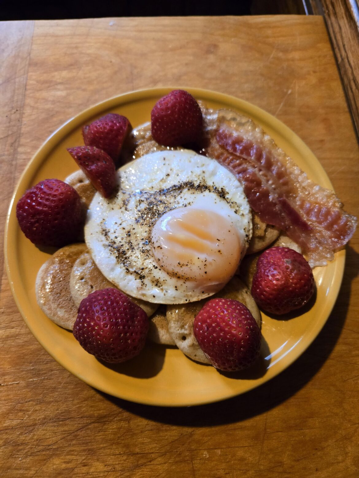 Duck egg on pancakes with bacon and fruit