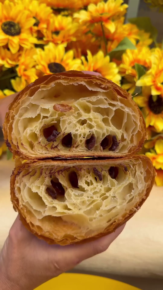 a person is holding a croissant that has been cut in half