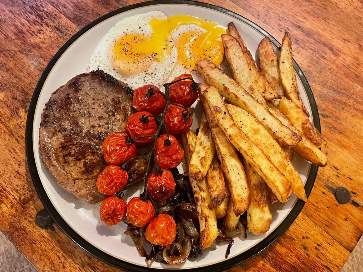 Steak & eggs with homemade chips, caramelised onions and roast tomatoes.