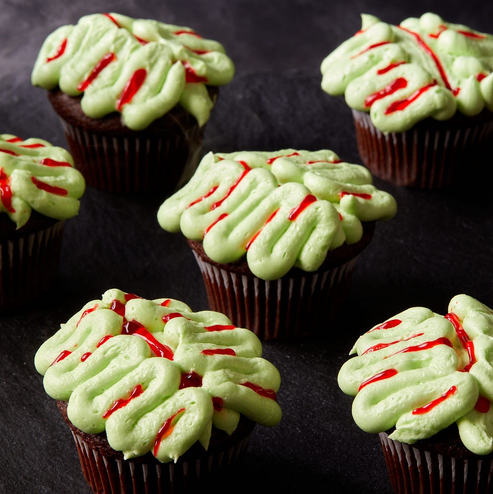 chocolate cupcakes decorated with green frosting and red gel food coloring to look like zombie brains