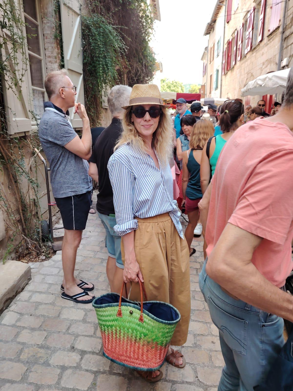 Woman in a striped shirt and straw hat in a French market.