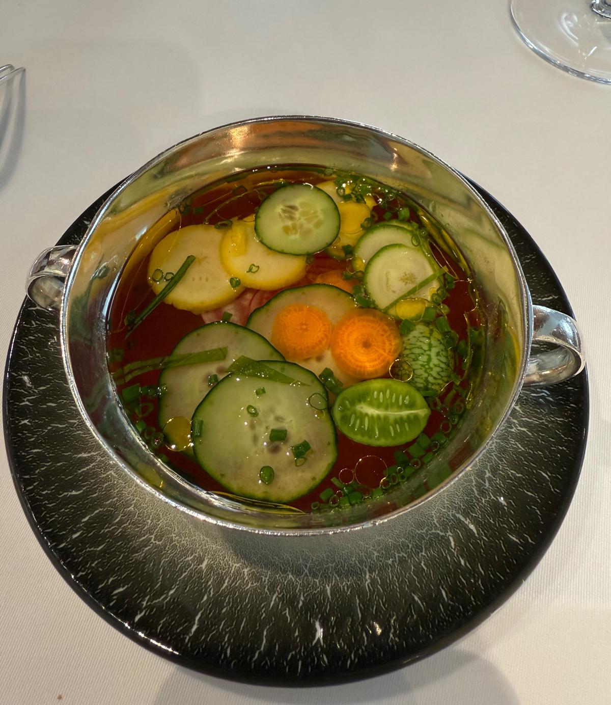 Vegetable broth in a silver bowl.