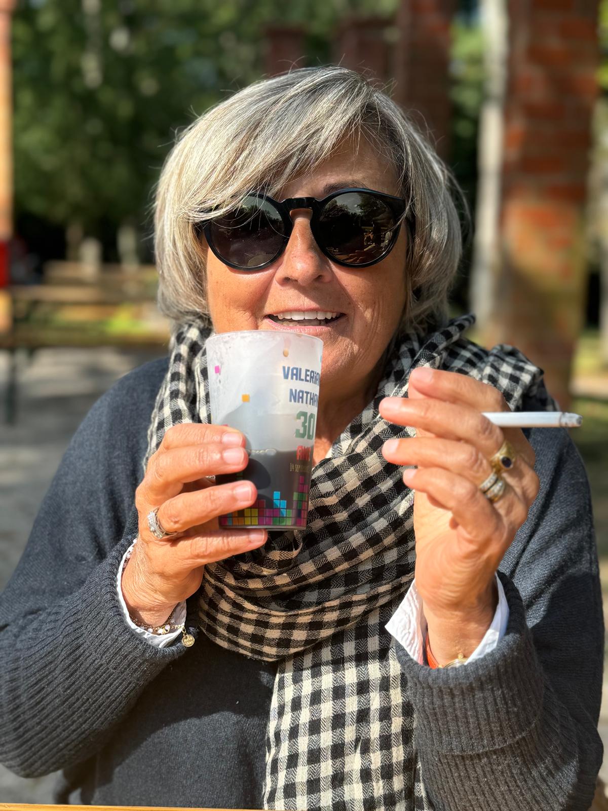 Françoise Molique smoking and drinking outdoors.