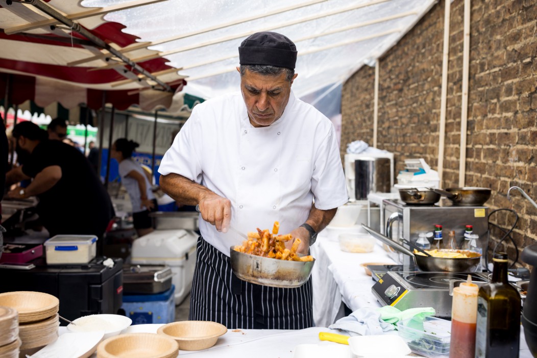 A cook prepares pasta at a food stall.