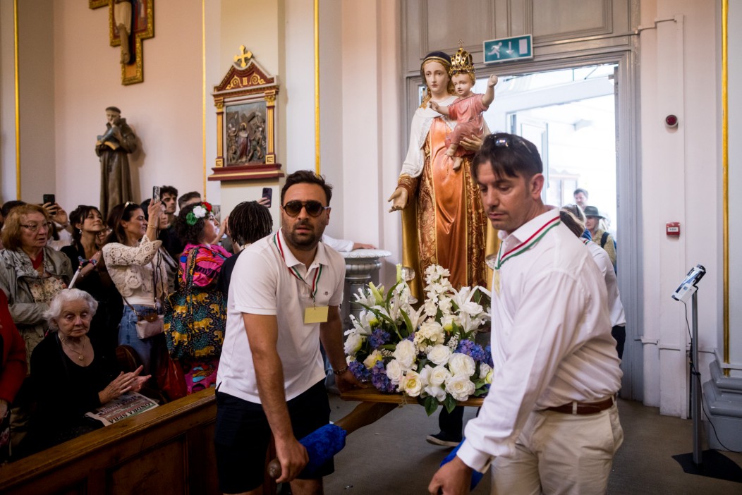 Procession carrying statue of the Virgin Mary and child in a church.