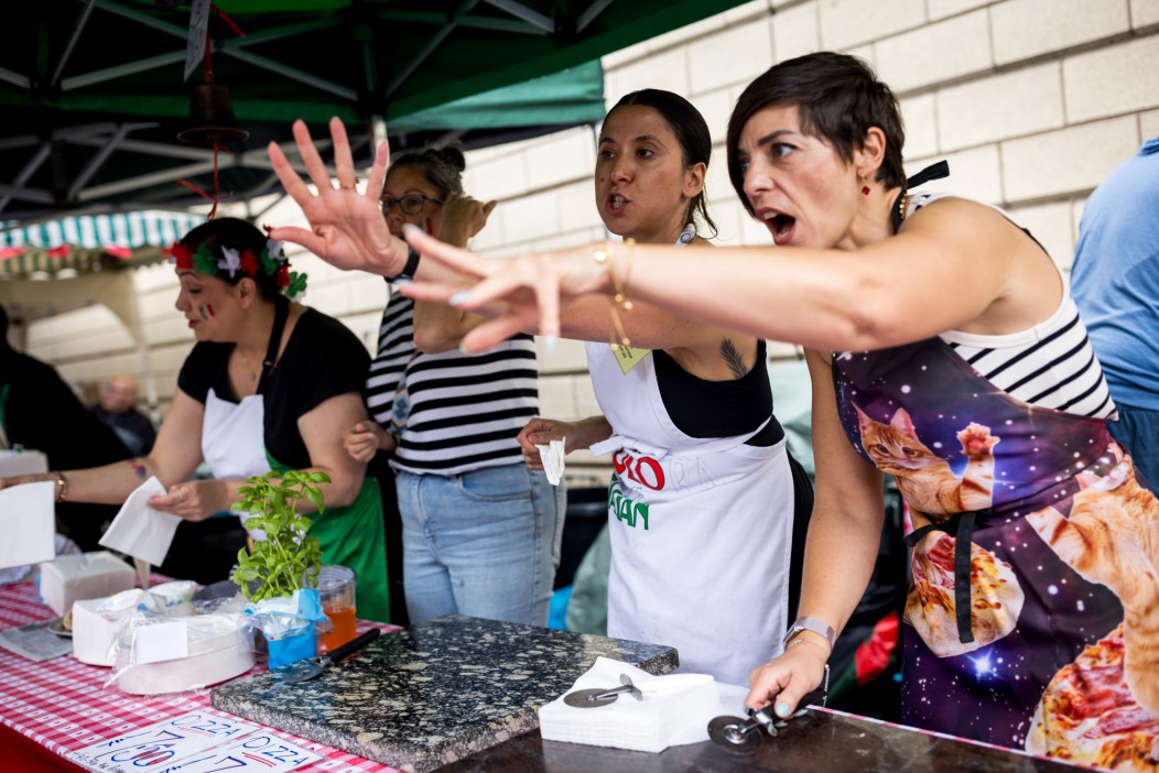 Women working at a pizza stall before a religious procession.