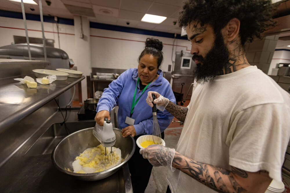 Culinary trainer Rebecca Queeney of The Snapchef Foundation helps Marino Pimentel mix ingredients for a dessert. (Jesse Costa/WBUR)