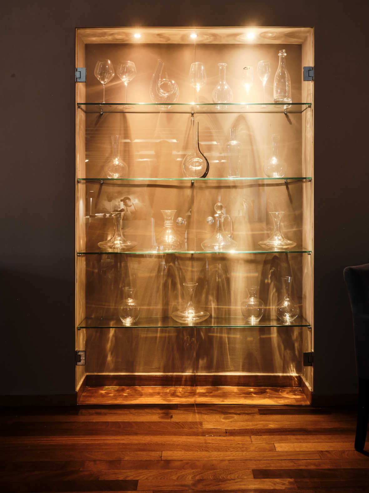 The cabinet of carafes gleams at night. © Botrini's