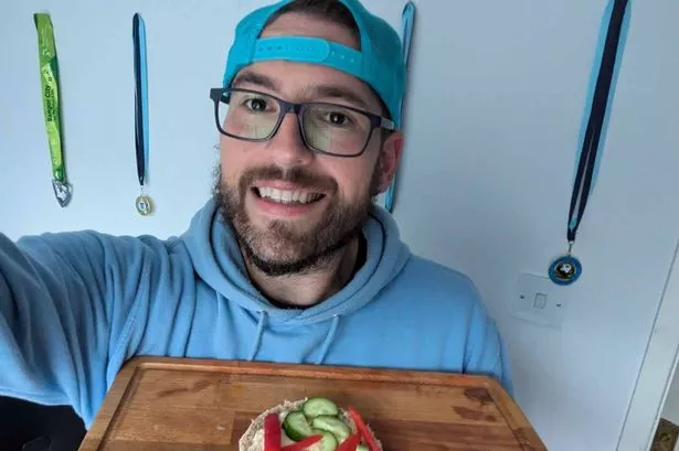 Man holding a chopping board with an open sandwich on.