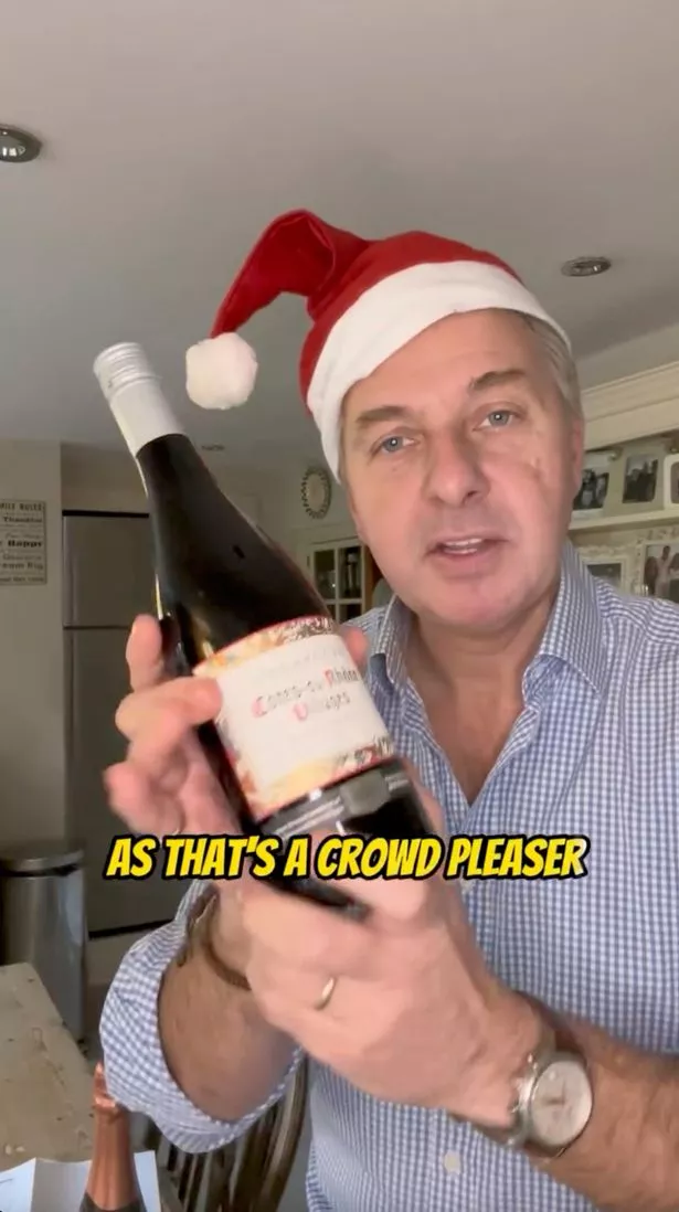 A picture of wine expert Andy Pincott wearing a Santa hat and holding a bottle of red wine up to his head