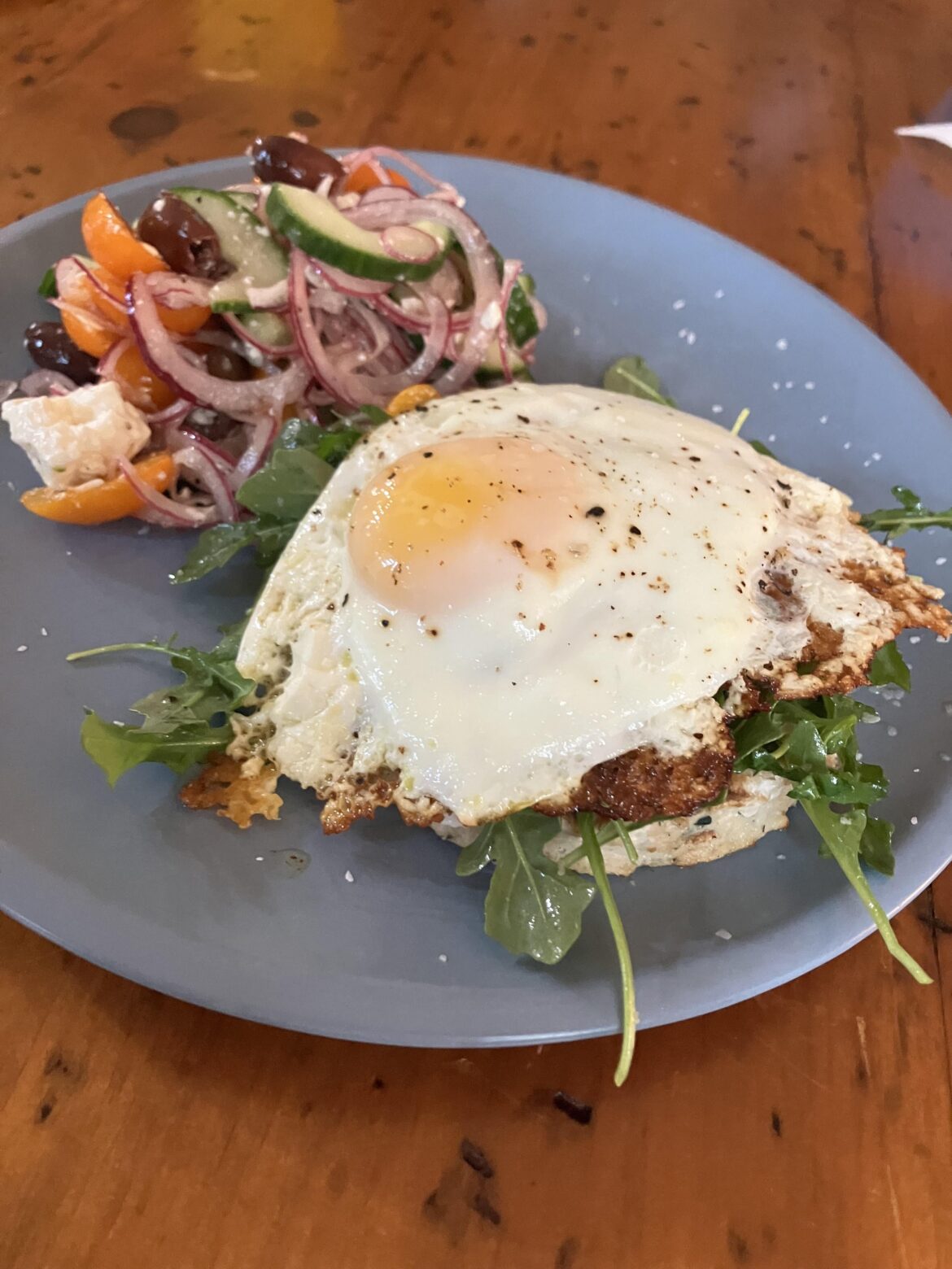 Crispy feta fried egg over a chicken burger with arugula