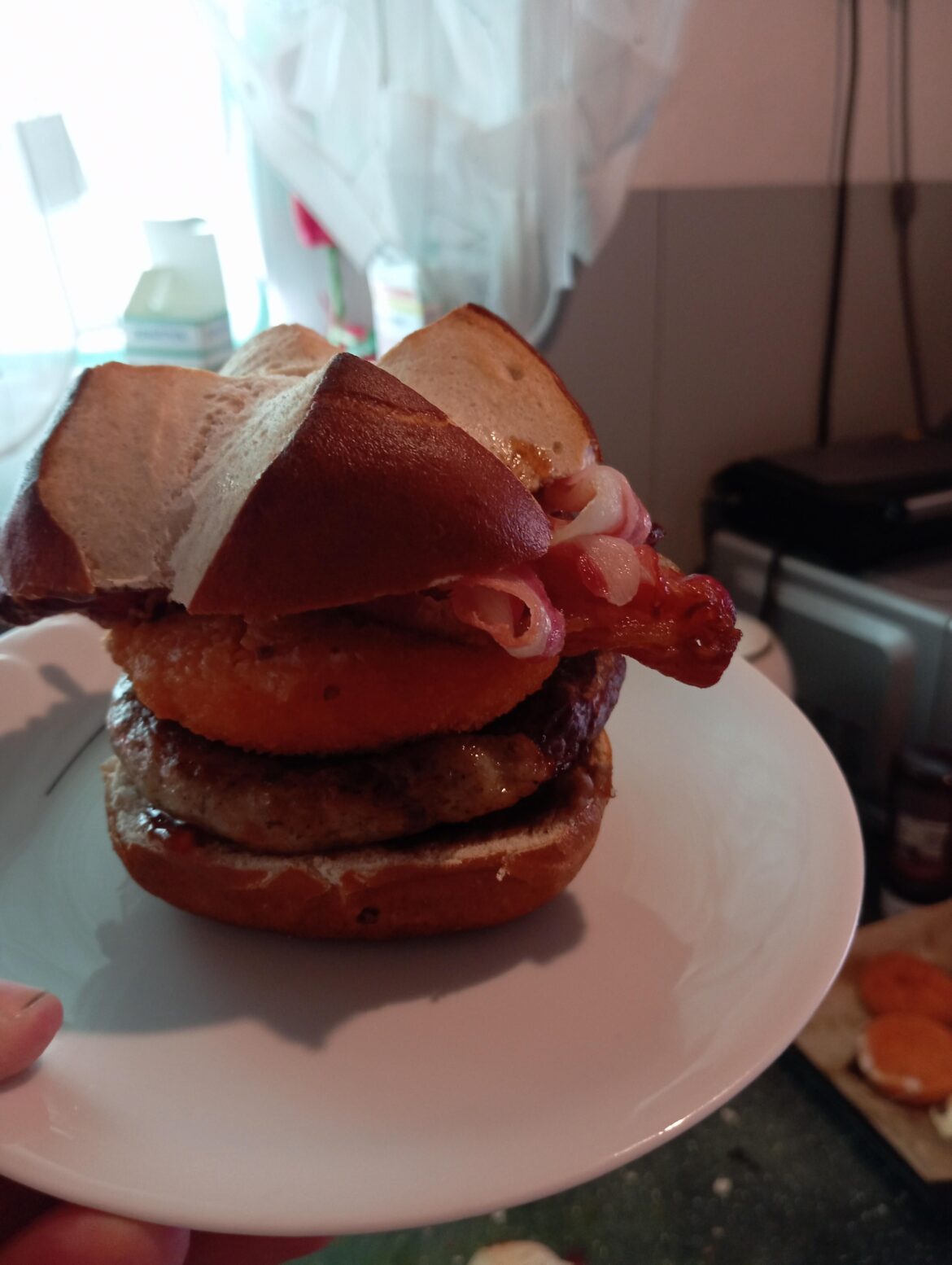 a snail sausage as a patty, with back camembert, air-fried bacon and sweet BBQ sauce with a pretzel bun