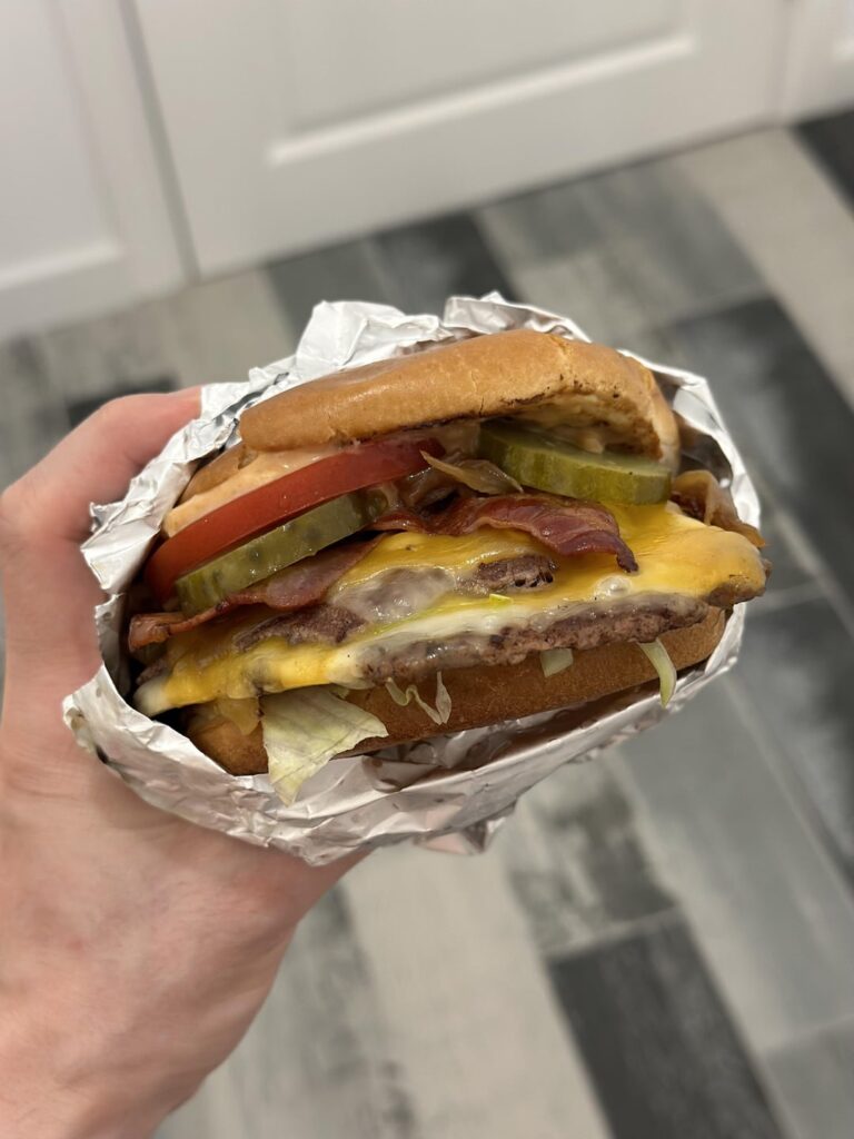 Toppings on a burger - unde or on top of the patty?