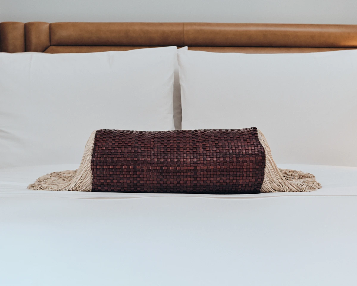 A woven accent pillow adds a touch of texture to the plush bed at W Rome