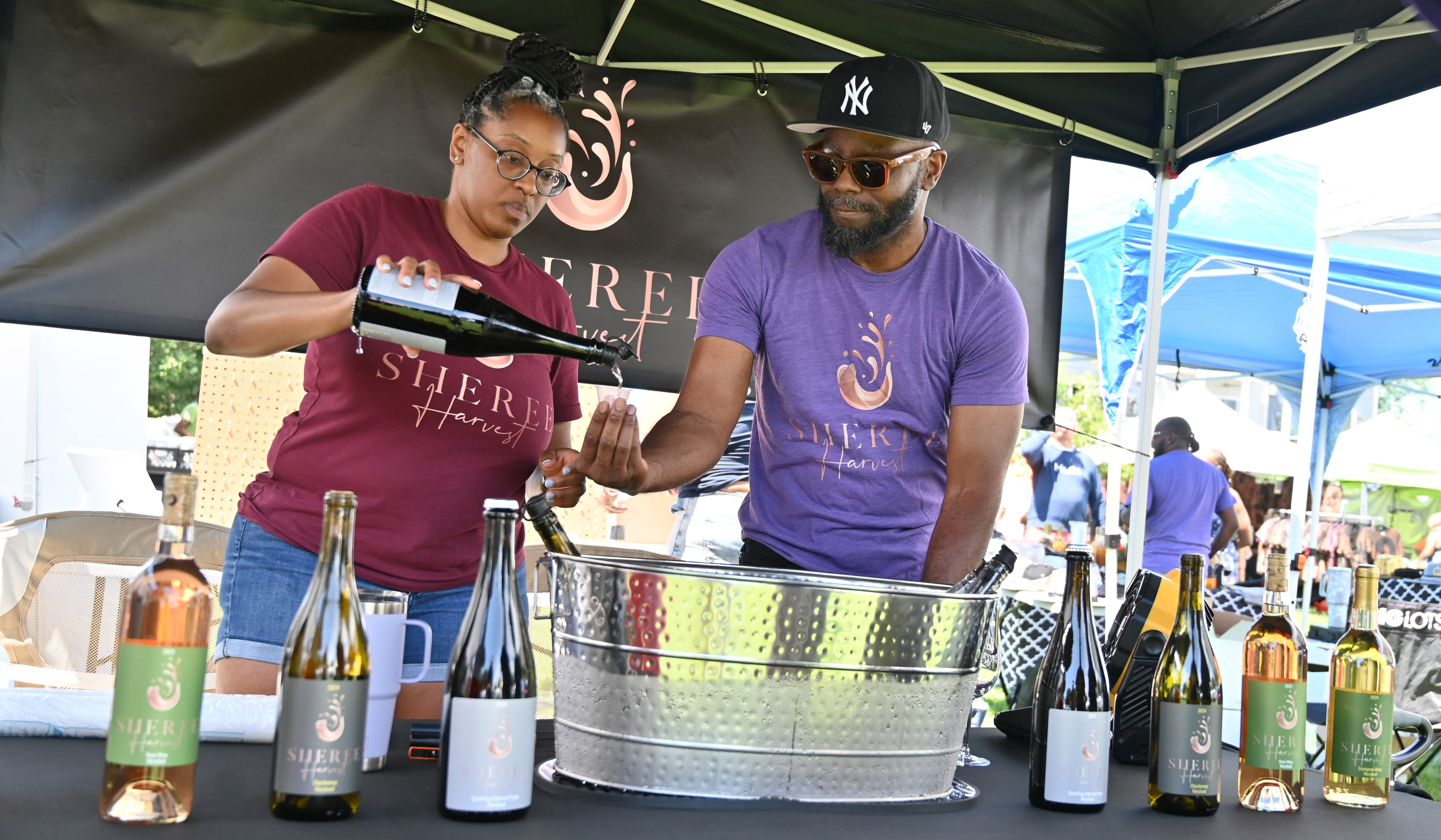 Sheree Cook, left, owner of Sheree Harvest gets assistance from her husband Takis, as they pour a sample for an antendee during the Arts, Wine Jazz & Soul Festival in Havre de Grace on Saturday. Proceeds from the event benefit the Havre de Grace Colored School Foundation. (Brian Krista/Staff)