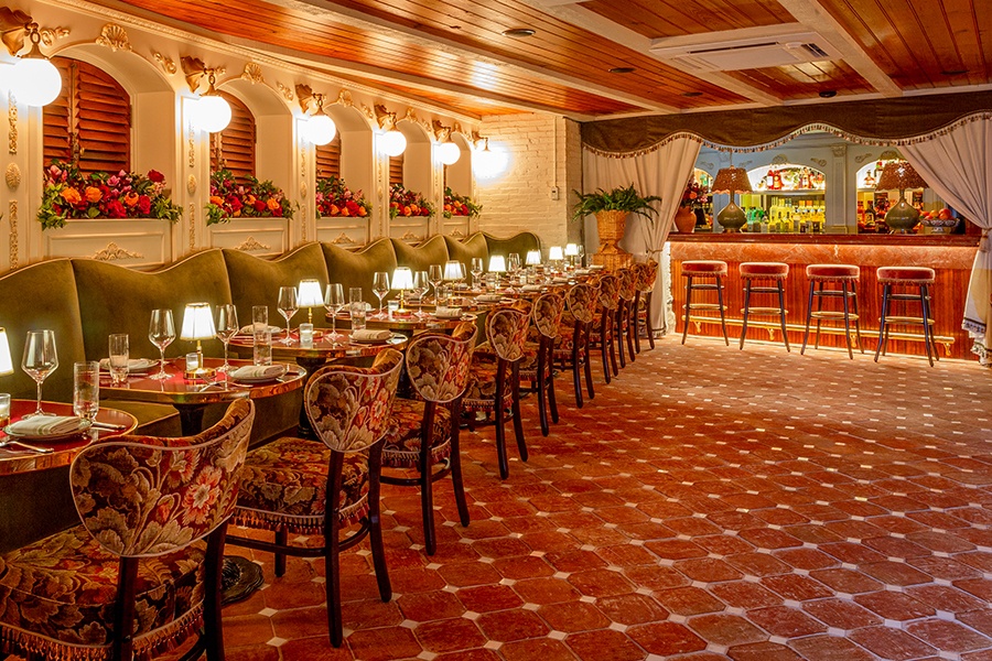 Interior of a restaurant featuring floral upholstery and lots of pale pink and green tones.