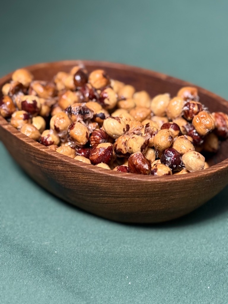 candied hazelnuts in a wooden bowl on a table with green tablecloth