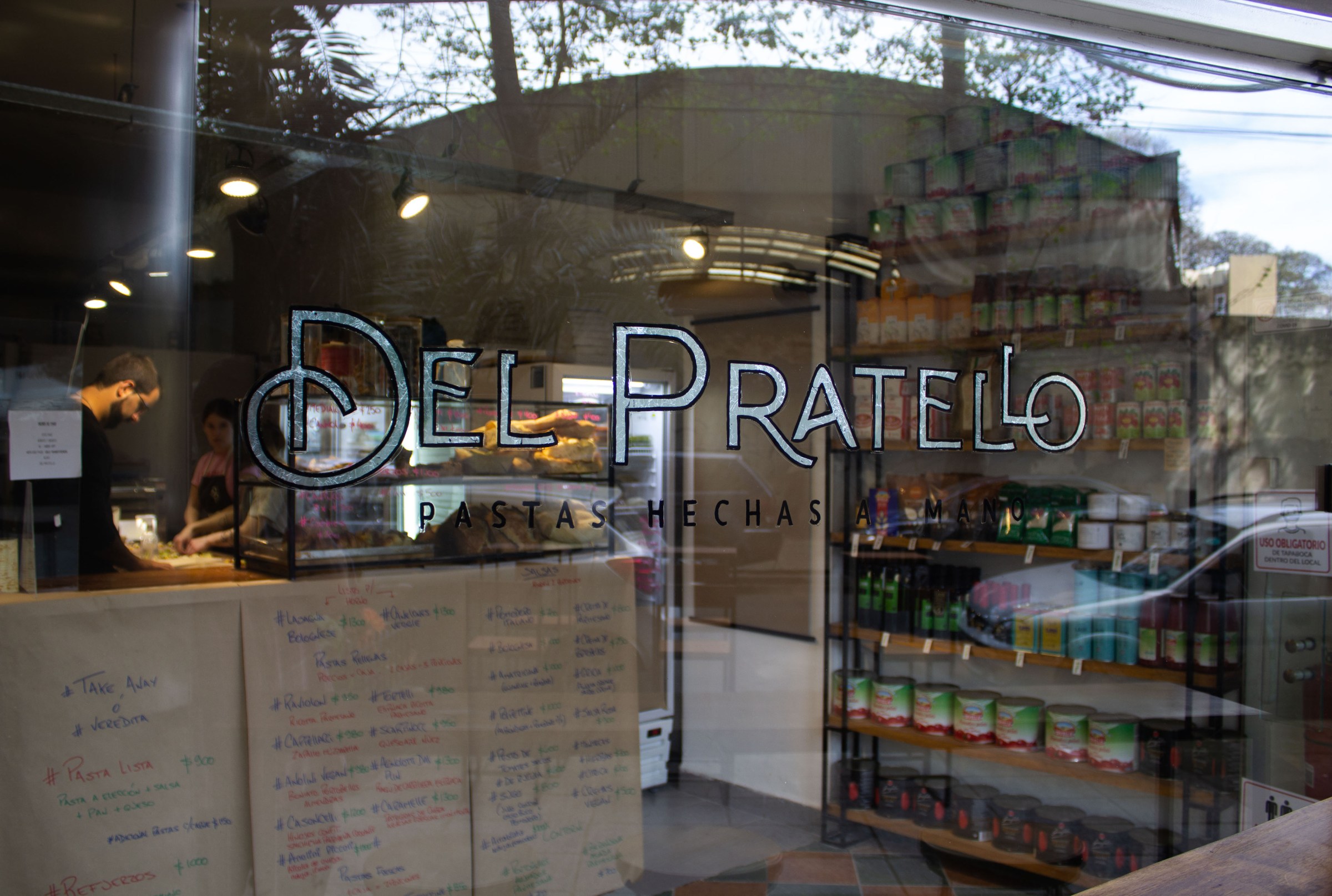 A shop exterior with the nam Del Pratello etched on the glass. 