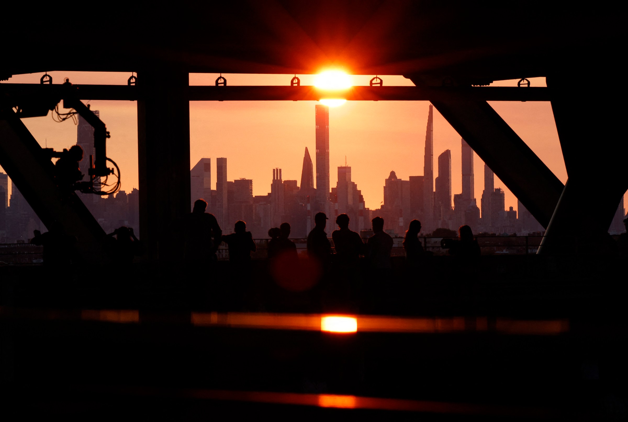 People watching a sunset behind a city skyline. 