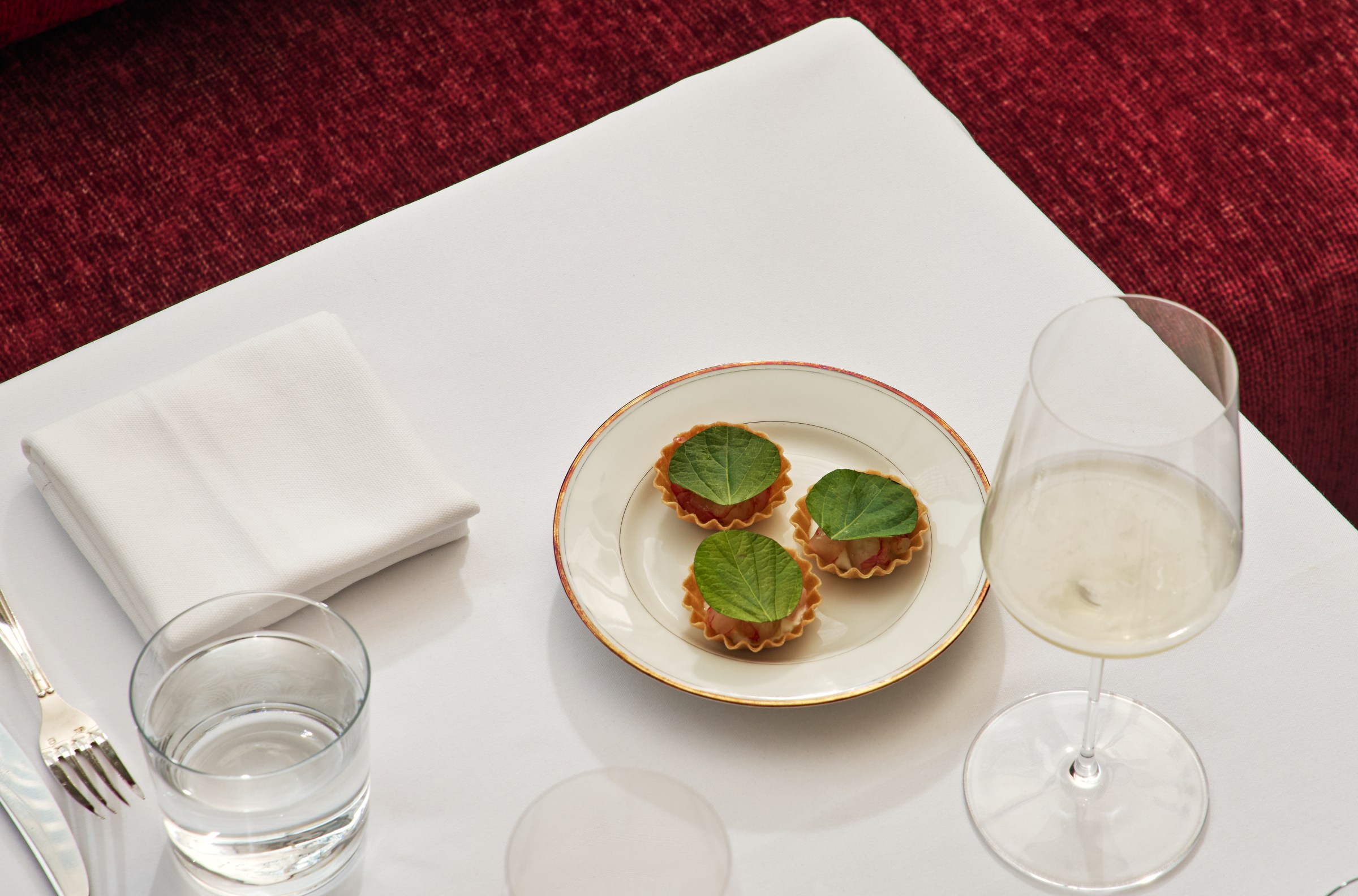 A table with a plate of three tarts with huge green leaves on top of them.