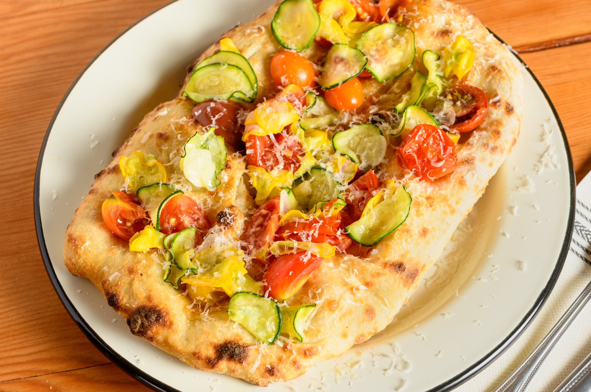 A pinsa topped with summer vegetables.
