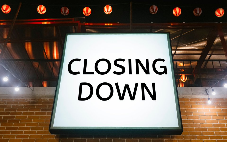 Closing Down sign on a brick wall.