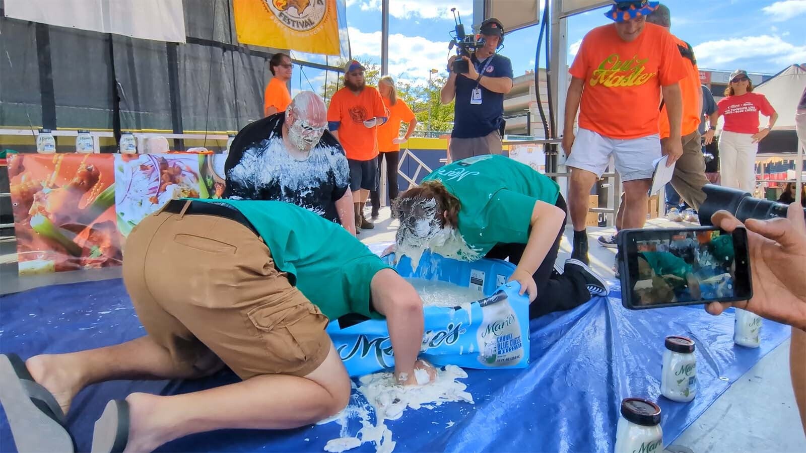 Andrew Beglin, left, emerged as the winner of the “Bobbing for Wings Contest,” and successfully found 20 chicken wings in a kiddie pool filled with bleu cheese while wearing swim goggles.