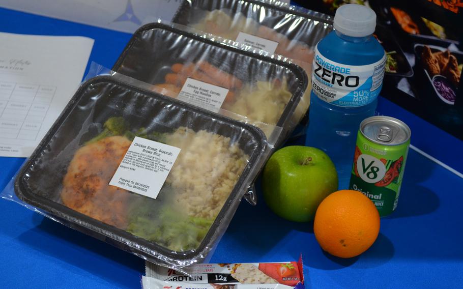 A display of meals in packaging with fruit and bottled drinks.