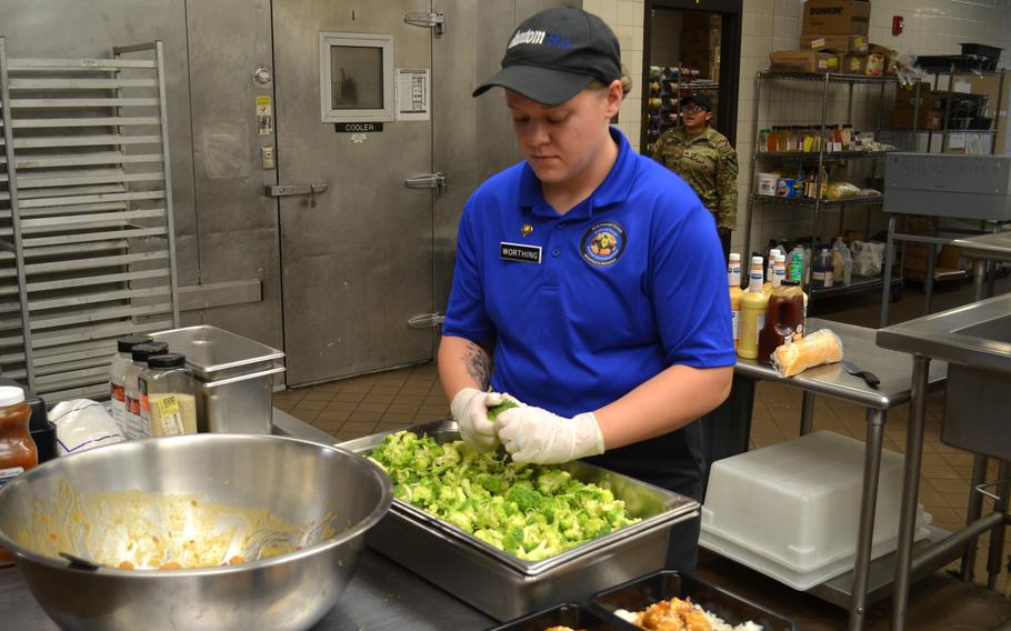 Food worker prepares broccoli.