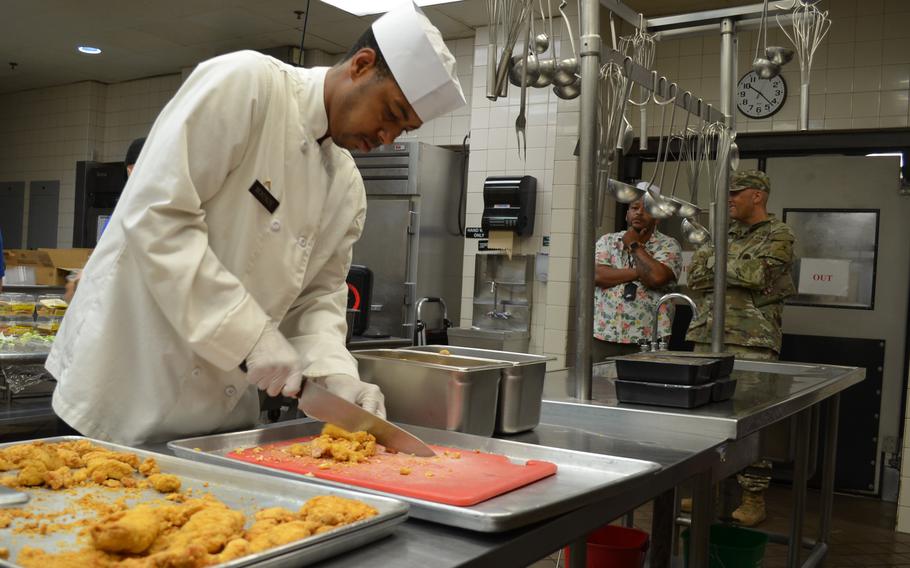A cook cuts chicken.