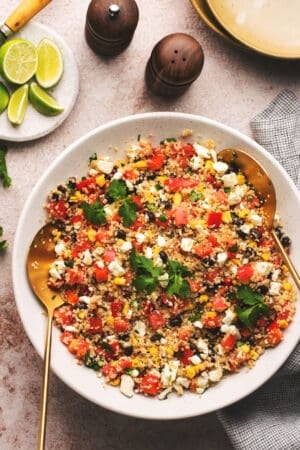 quinoa salad in a bowl with lime wedges on table