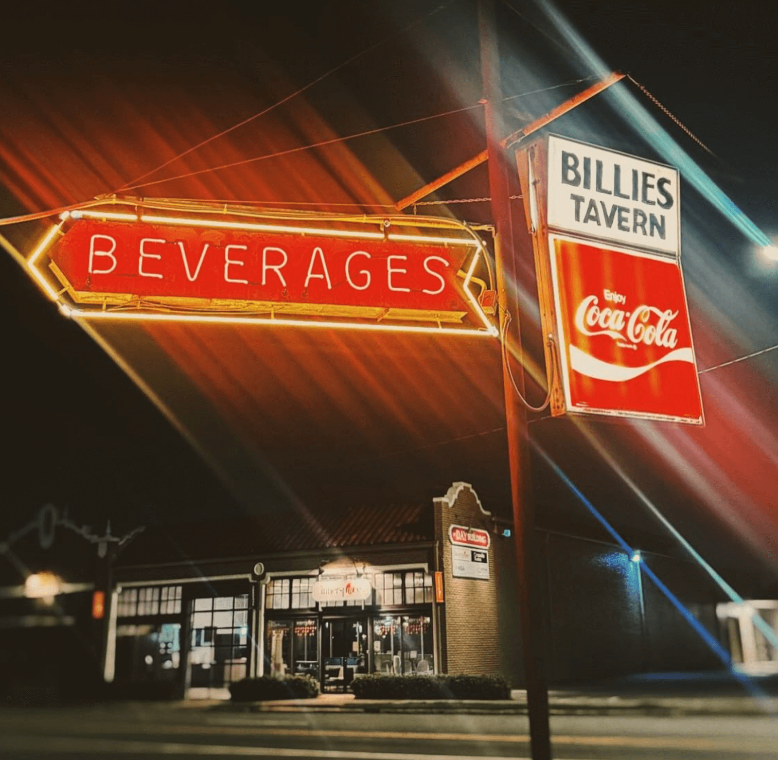 Neon "Beverages" and "Billies Tavern" signs with the Coca-Cola logo shine at night, capturing the classic charm found in many Birmingham restaurants and unique dining concepts across the city.