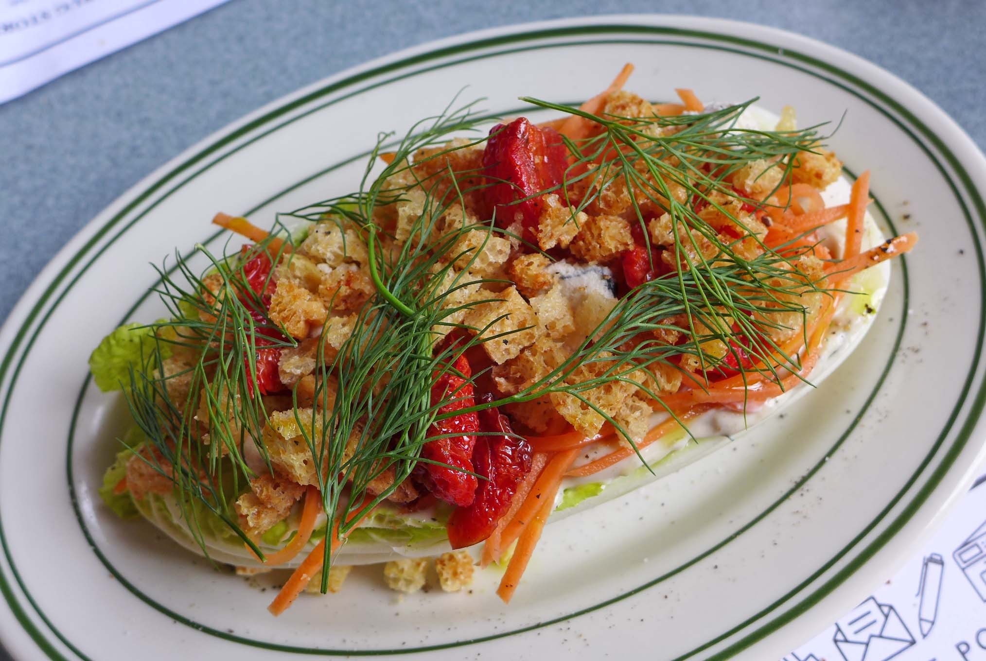 An oblong salad heaped with herbs, tomatoes, and croutons.