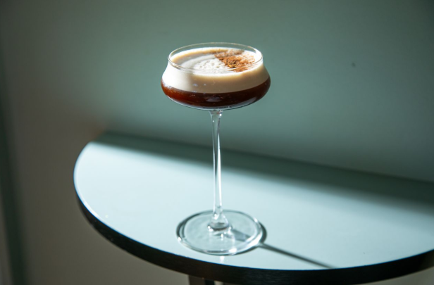 A brown cocktail with white froth in a stemmed cocktail glass 