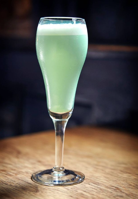a light green cocktail with white froth in a tall odd shaped glass