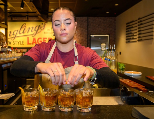 Bartender Taylor makes Old Fashioned drinks, one of the menu...