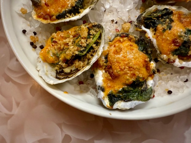 Chef Paul Benton of Zoes Steak & Seafood crafts Zoes Rockefeller. Here, local Laughing King oysters are topped with braised kale, pimento cheese, chicharrón, and bacon. Nestled in the cup of their shell, the dish is broiled until bubbling. (Patrick Evans-Hylton / freelance)