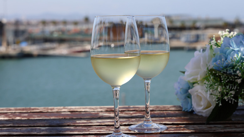 Two glasses of white wine with harbor in background