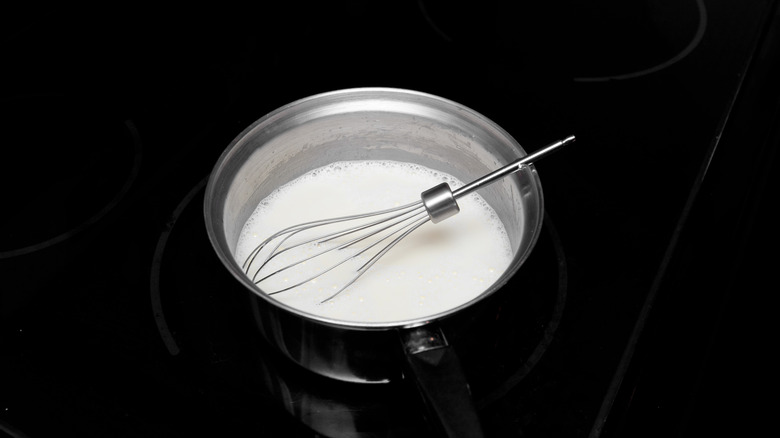 heavy cream in a saucepan with a metal whisk
