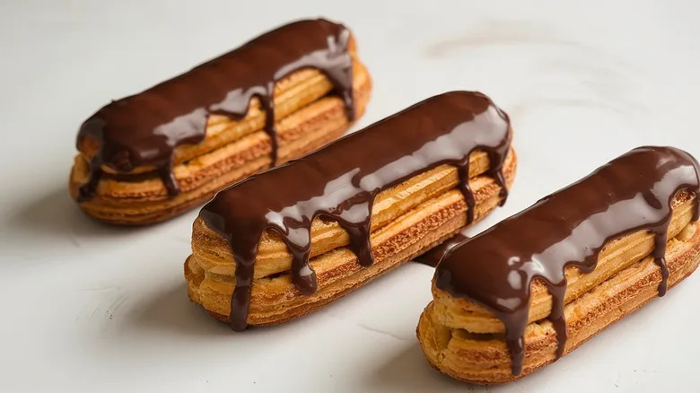 A close-up of three eclairs with chocolate glaze