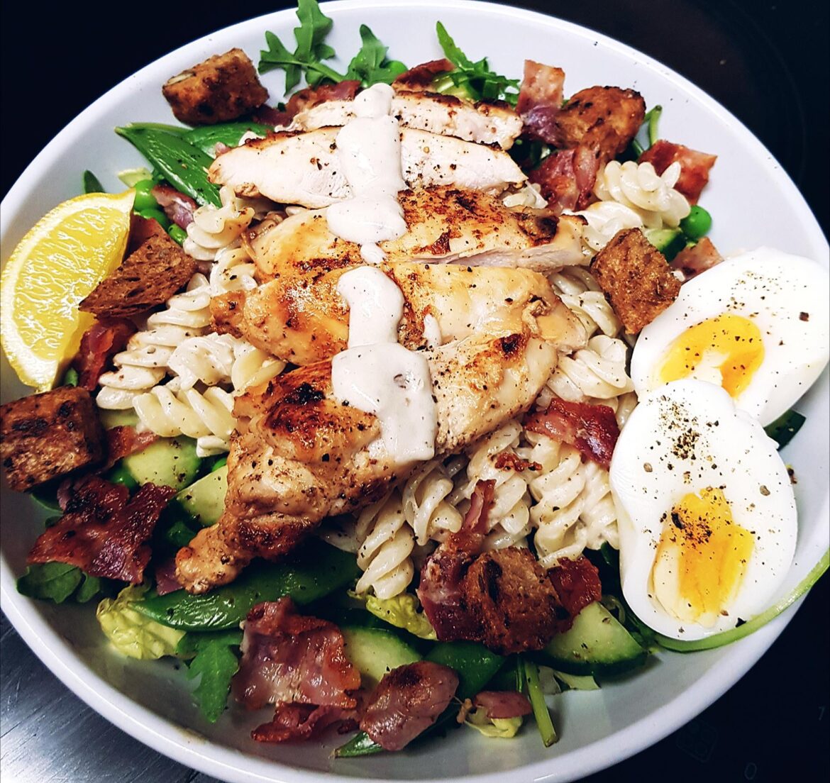 Unconventional Caesar Salad - Grilled Chicken, Pasta, Bacon, Peas, Snap Peas, Cucumber, Lettuce and Rocket, Homemade Caesar Dressing and Soft Boiled Eggs. Seeded Croutons to Finish.