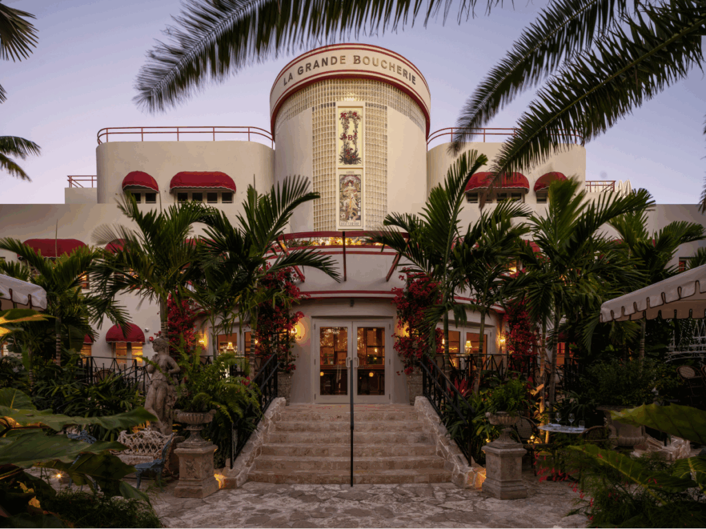 view of circular building with red awnings, surrounded by palm trees and greenery