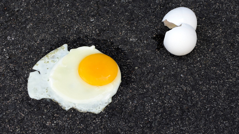 A fried egg on pavement with a cracked shell