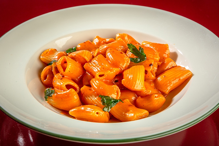 A bowl of thick rigatoni in a red-orange sauce.