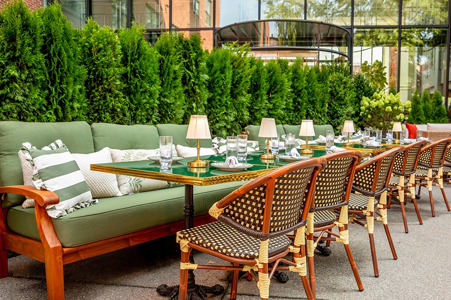 Green lounge seating and tables on an outdoor restaurant patio.