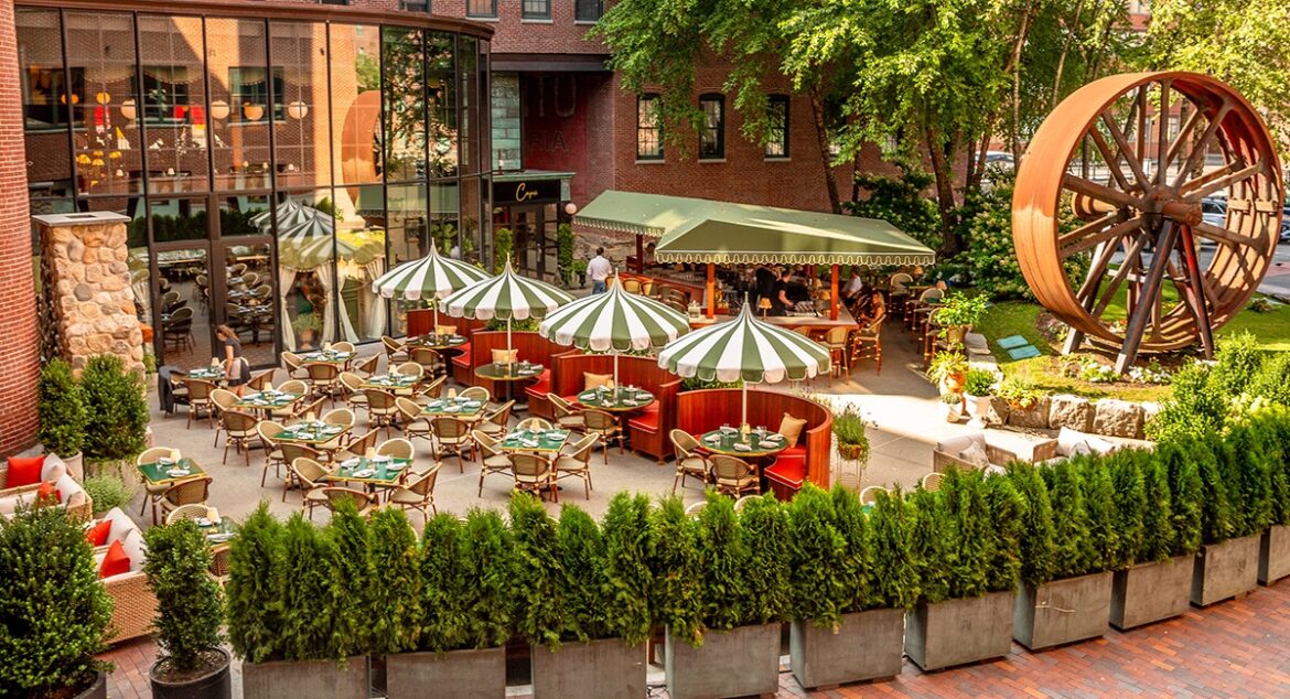 An Italian-inspired large restaurant patio with green-and-white -striped umbrellas and u-shaped red booths.