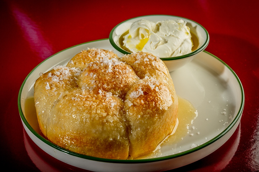Pull-apart rolls are drizzled in honey, cheese, and sea salt, served with a bowl of ricotta.